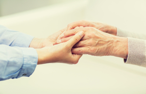 people, age, family, care and support concept - close up of senior and young woman holding hands